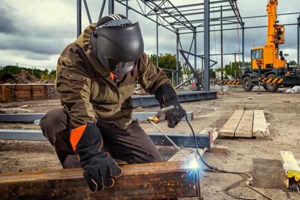 A,Young,Man,Welder,In,Brown,Uniform,,Welding,Mask,And